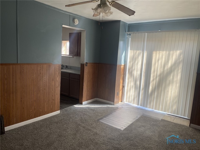 1455 Oak St, Toledo, OH 43605 - empty room featuring carpet, a wainscoted wall, a sink, wooden walls, and ceiling fan