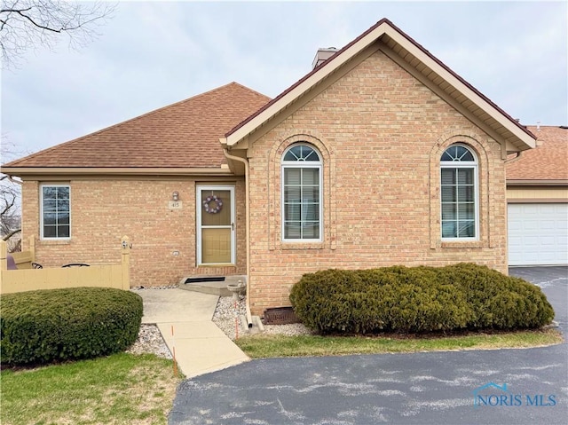 view of front of home featuring a garage, driveway, a shingled roof, and brick siding