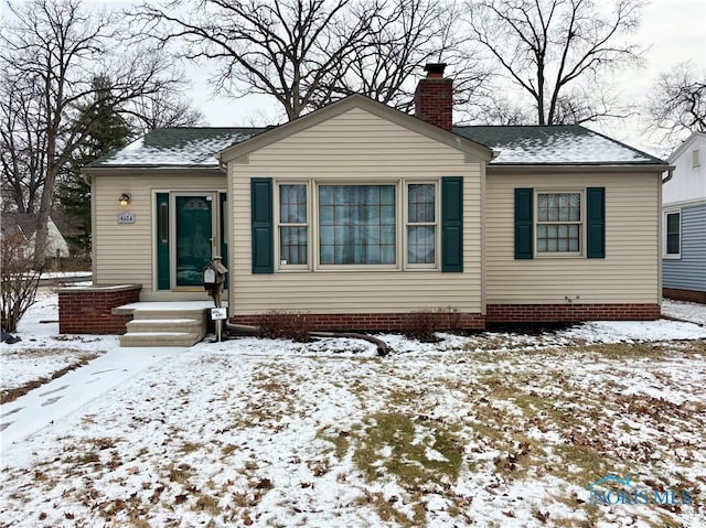 bungalow with a shingled roof and a chimney