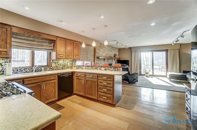 kitchen with sink, hanging light fixtures, kitchen peninsula, dishwasher, and backsplash