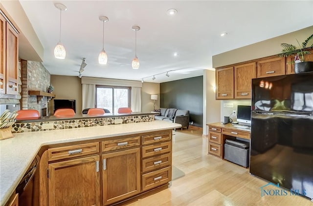 kitchen with decorative light fixtures, track lighting, black appliances, and light hardwood / wood-style floors