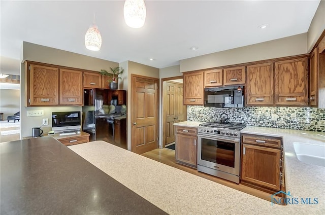 kitchen featuring pendant lighting, backsplash, and black appliances