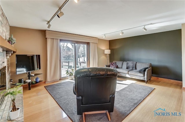 living room with hardwood / wood-style flooring, rail lighting, and a brick fireplace