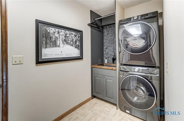 laundry room with cabinets, stacked washing maching and dryer, and sink