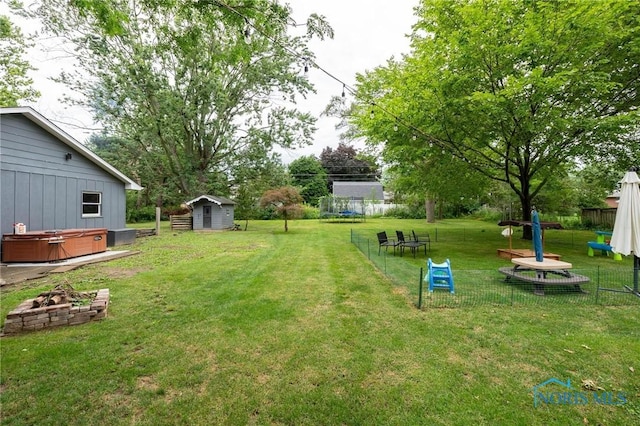 view of yard featuring a trampoline, a storage shed, and a hot tub