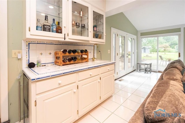 kitchen with vaulted ceiling, sink, decorative backsplash, light tile patterned floors, and french doors