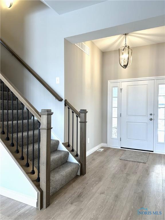 entryway featuring wood-type flooring, a wealth of natural light, and a chandelier