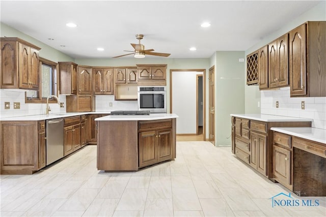 kitchen with sink, a center island, ceiling fan, stainless steel appliances, and decorative backsplash