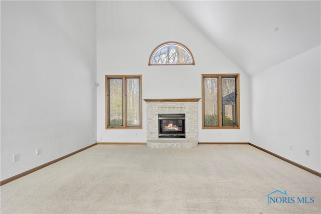 unfurnished living room featuring a brick fireplace, light colored carpet, and high vaulted ceiling