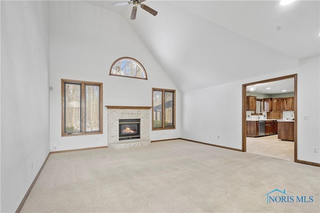 unfurnished living room with ceiling fan, light colored carpet, a fireplace, and high vaulted ceiling