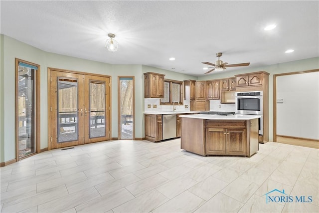 kitchen with sink, ceiling fan, stainless steel appliances, a center island, and french doors