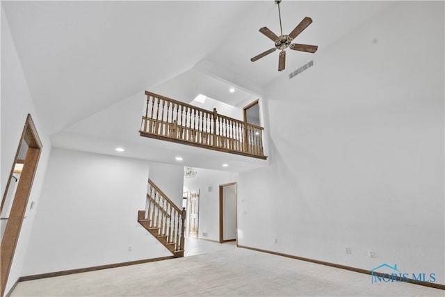 unfurnished living room featuring ceiling fan, light colored carpet, and high vaulted ceiling