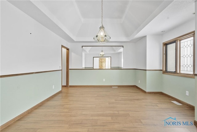 spare room featuring light hardwood / wood-style flooring and a tray ceiling