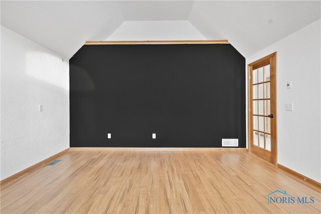 spare room featuring vaulted ceiling and light hardwood / wood-style flooring