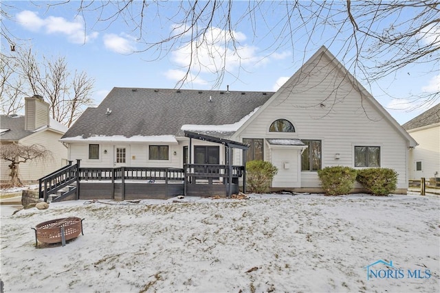 snow covered back of property featuring a wooden deck and an outdoor fire pit