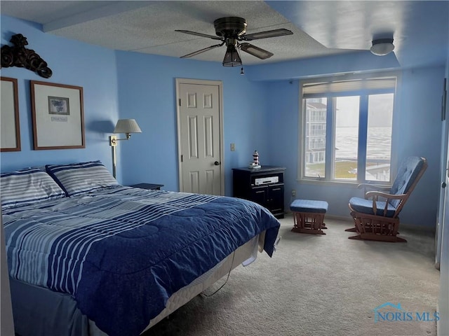 bedroom with a water view, ceiling fan, carpet, and a textured ceiling