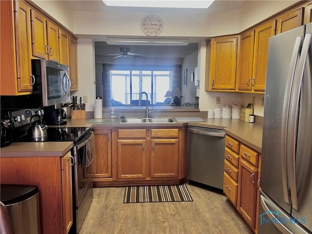 kitchen with ceiling fan, appliances with stainless steel finishes, sink, and light hardwood / wood-style floors