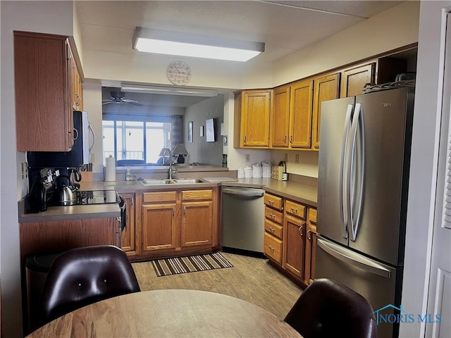 kitchen featuring appliances with stainless steel finishes, sink, ceiling fan, and light hardwood / wood-style flooring