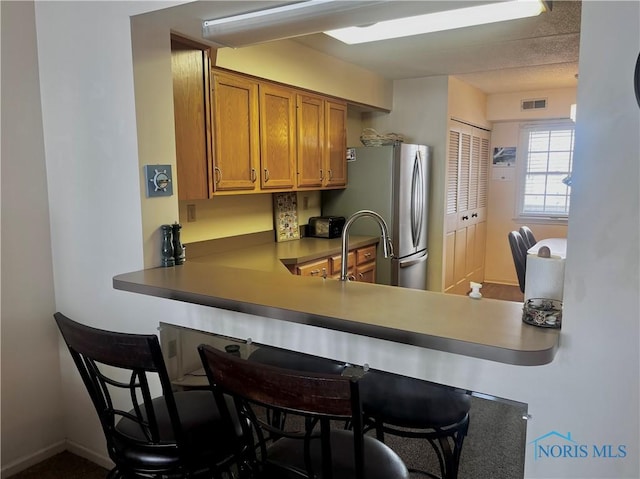 kitchen with stainless steel refrigerator, kitchen peninsula, and a breakfast bar area