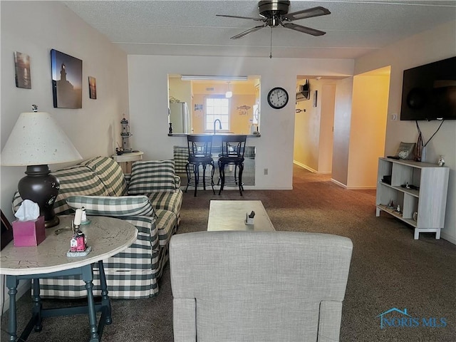 living room featuring ceiling fan, dark carpet, and a textured ceiling