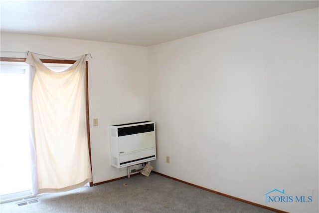 unfurnished room featuring heating unit and light colored carpet