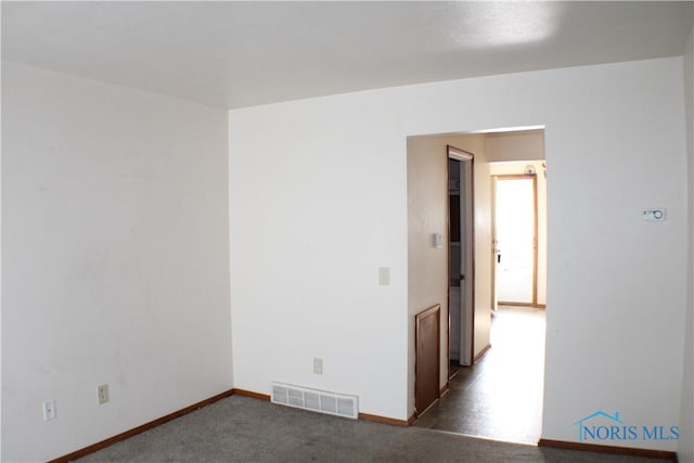 spare room featuring dark colored carpet