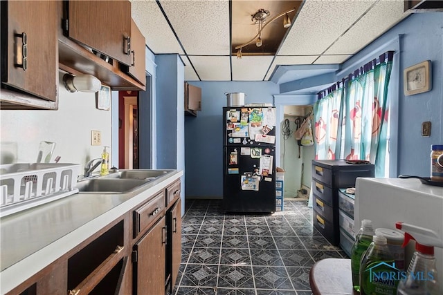 kitchen featuring black refrigerator, sink, dark tile patterned flooring, and a drop ceiling