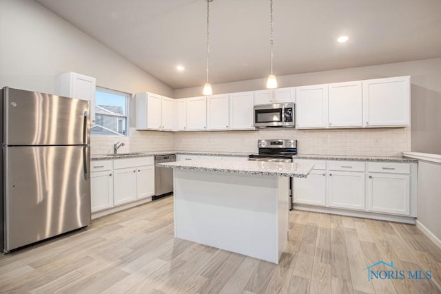 kitchen featuring white cabinetry, a kitchen island, pendant lighting, stainless steel appliances, and light stone countertops