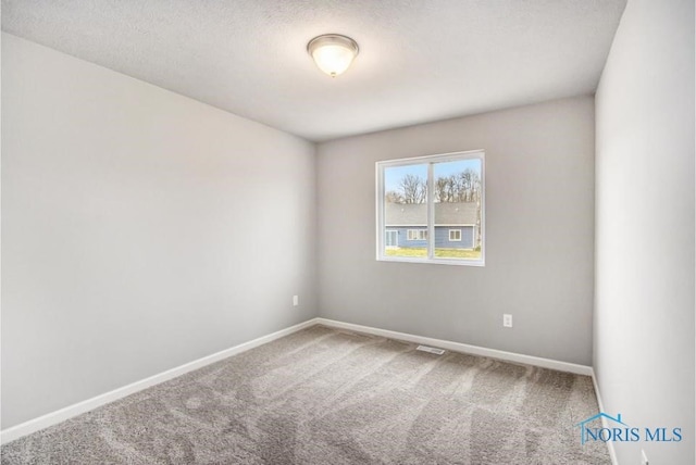 carpeted empty room with baseboards, a textured ceiling, and visible vents