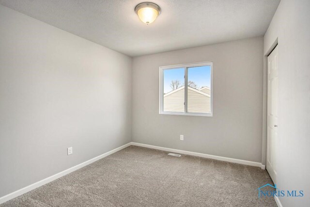 spare room featuring carpet flooring and a textured ceiling