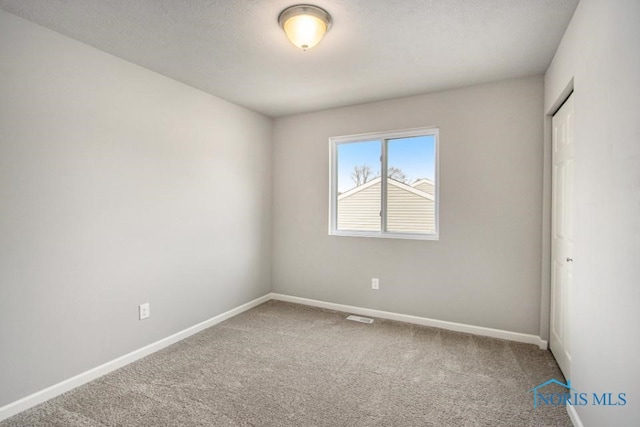 carpeted spare room featuring baseboards and visible vents