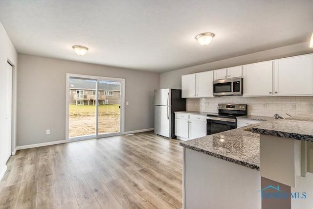 kitchen with baseboards, dark stone countertops, tasteful backsplash, and stainless steel appliances