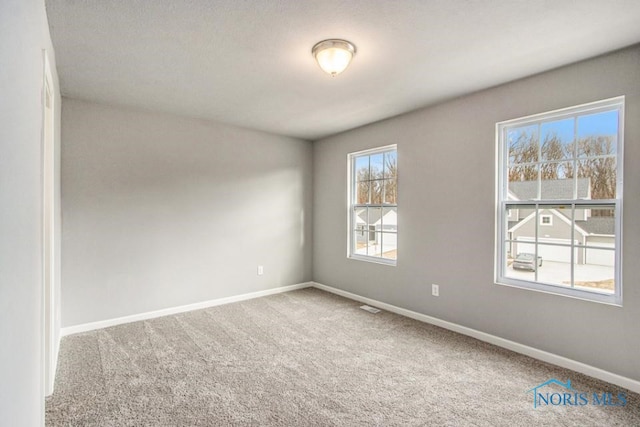 carpeted spare room featuring baseboards