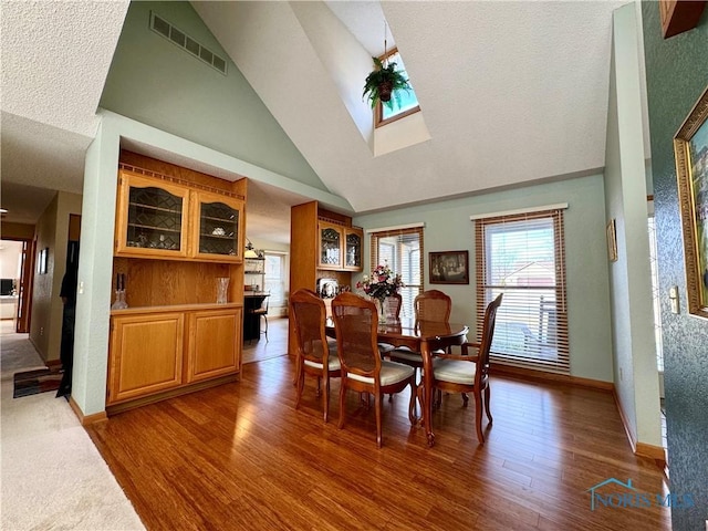 dining room with dark hardwood / wood-style floors and high vaulted ceiling