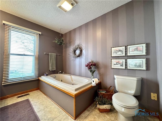 bathroom with tile patterned floors, toilet, a bathtub, and a textured ceiling