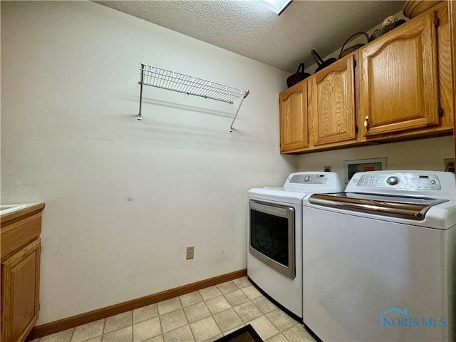 washroom featuring cabinets, washing machine and dryer, and a textured ceiling