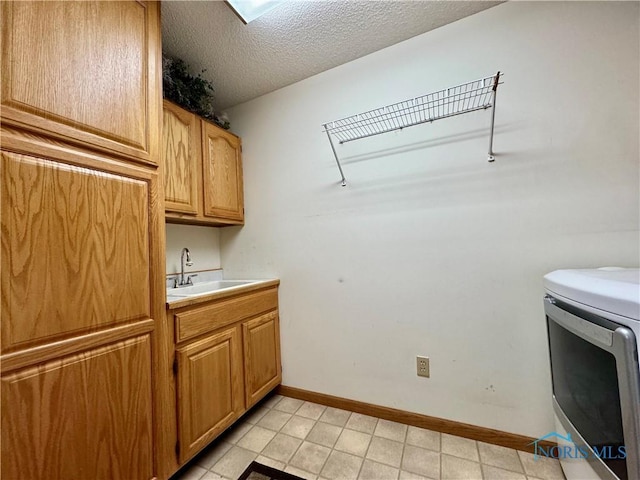 clothes washing area featuring sink, washer / dryer, cabinets, and a textured ceiling