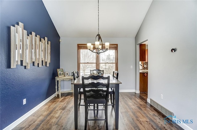 dining room with lofted ceiling, dark hardwood / wood-style flooring, and a chandelier