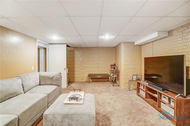 living room with brick wall, a drop ceiling, and carpet floors