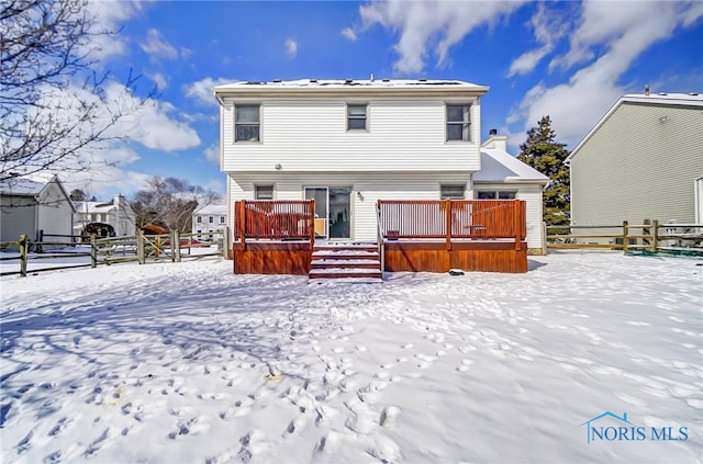 snow covered rear of property with a wooden deck