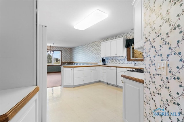 kitchen with pendant lighting, dishwasher, kitchen peninsula, and white cabinets