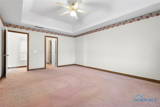 carpeted empty room with ceiling fan and a tray ceiling