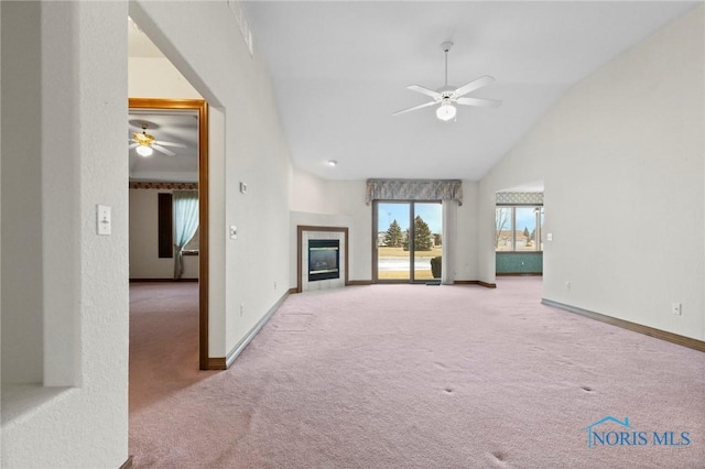 unfurnished living room featuring ceiling fan, a tiled fireplace, high vaulted ceiling, and carpet