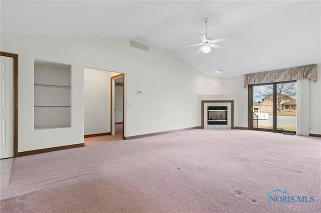 unfurnished living room featuring lofted ceiling, light colored carpet, built in features, ceiling fan, and a fireplace