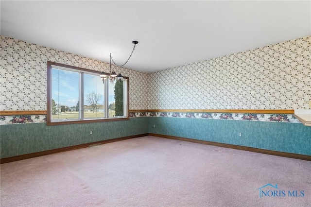 spare room featuring carpet floors and a chandelier