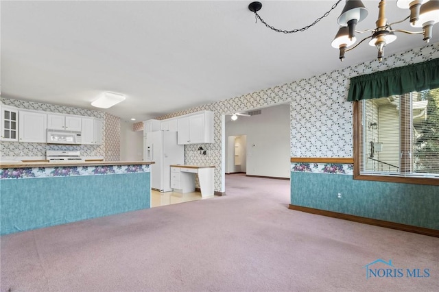 kitchen featuring white appliances, white cabinets, light carpet, decorative backsplash, and a chandelier