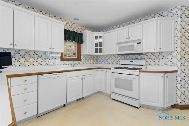 kitchen with white cabinetry, white appliances, and sink