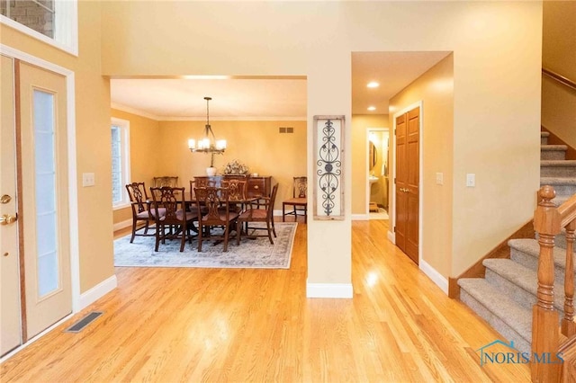 dining area featuring crown molding, an inviting chandelier, and light hardwood / wood-style flooring