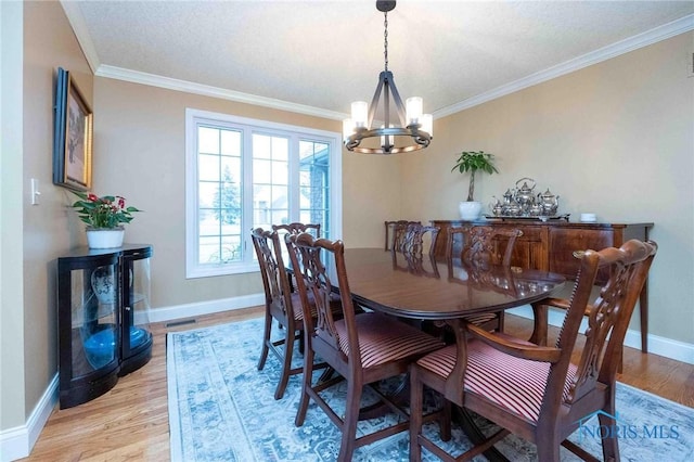 dining room featuring a notable chandelier, ornamental molding, and light hardwood / wood-style floors