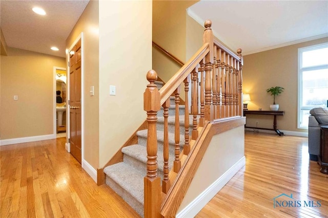 staircase with wood-type flooring and ornamental molding